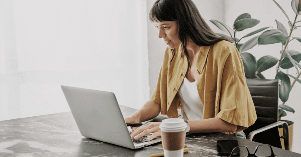 Une dame assise à un bureau utilise un portable