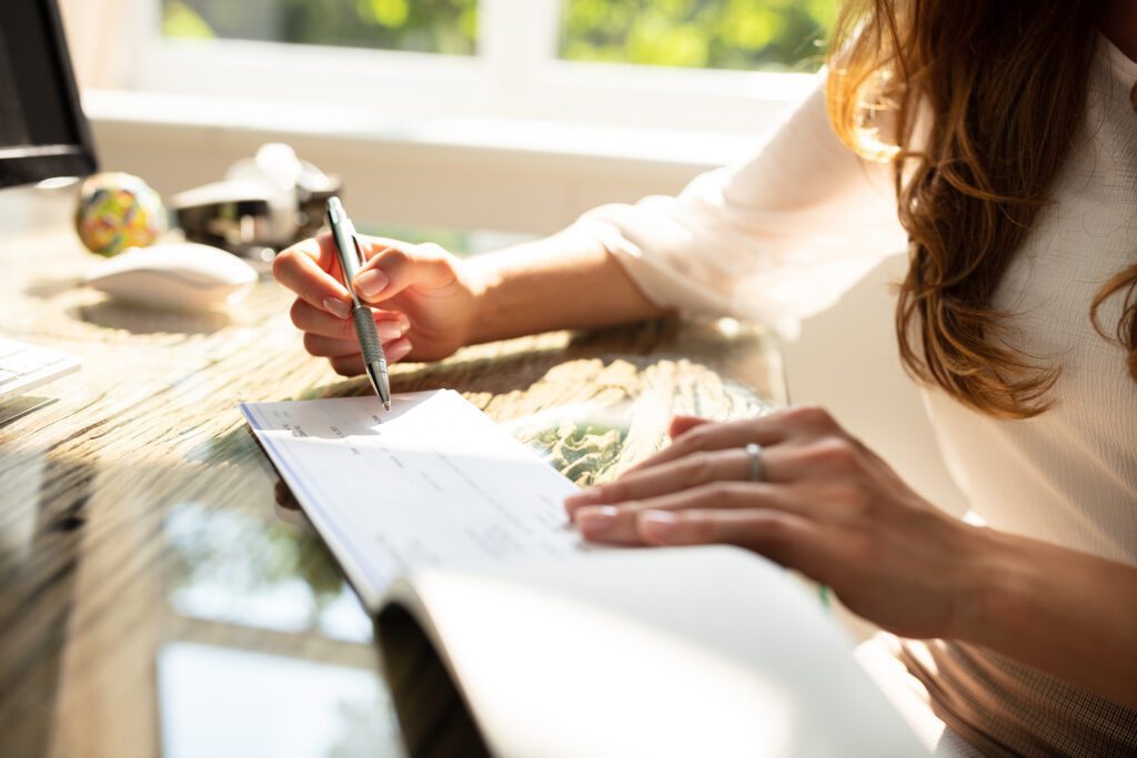 A desk is littered with receipts and other papers; a man’s hand works a calculator.