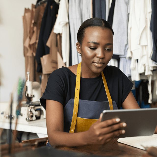 A clothing designer works on her tablet, using fintech solutions to support her small business.