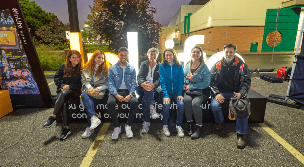 Interac Chief Human Resources Officer Caroline Stephens sits with fellow Interac employees outdoors