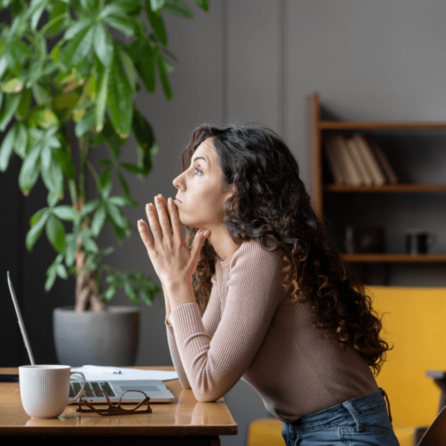 A woman sitting at a desk looks frustrated. 86% of Canadians report feeling 'fraud fatigue.'