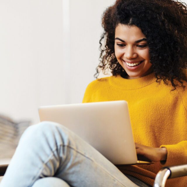 Smiling woman in yellow sweater transacting confidently and securely online.