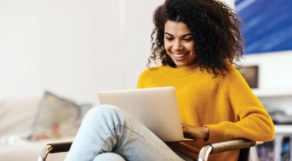 Femme souriante portant un chandail jaune transigeant avec confiance et sécurité en ligne.